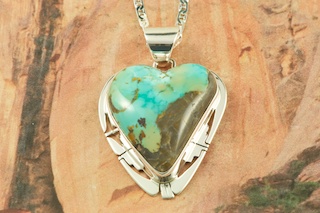 Genuine Candelaria Boulder Turquoise set in Sterling Silver Pendant. The cabochon is Candelaria Boulder Turquoise, you can see the veins of Turquoise running through the host rock.  The Candelaria mine is located in Esmeralda County, Nevada. Created by Navajo Artist Phillip Sanchez. Signed by the artist. Free 18 inch Sterling Silver Chain with purchase of pendant.
